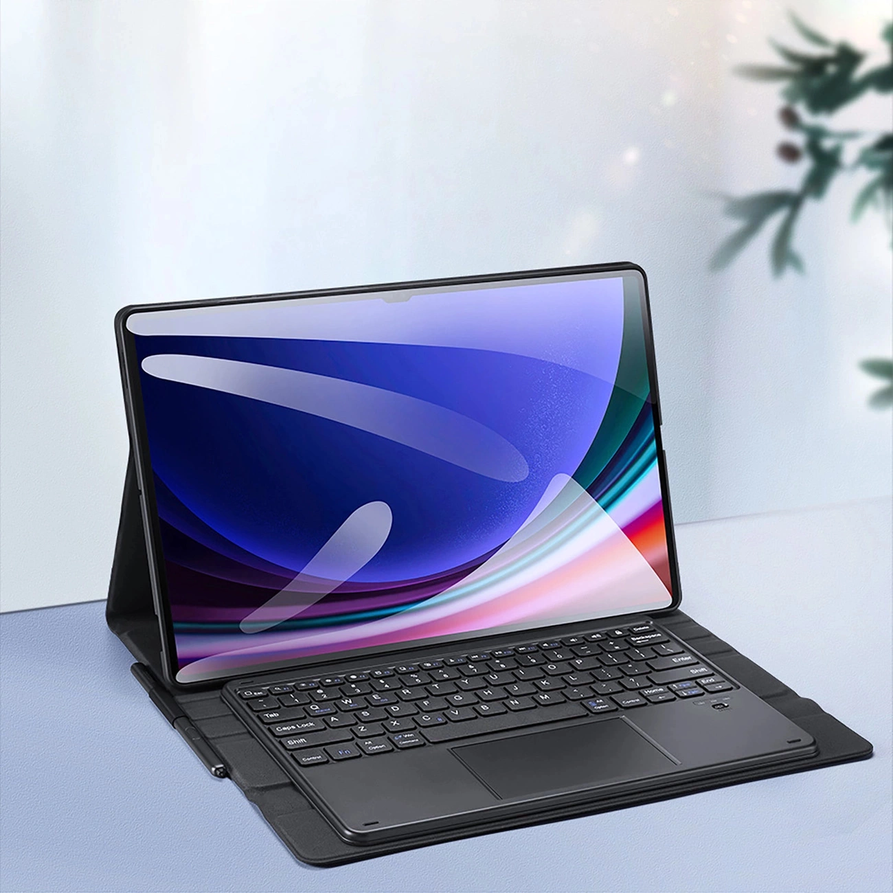 Un tablet con custodia tastiera e schermo colorato poggia su una superficie chiara.