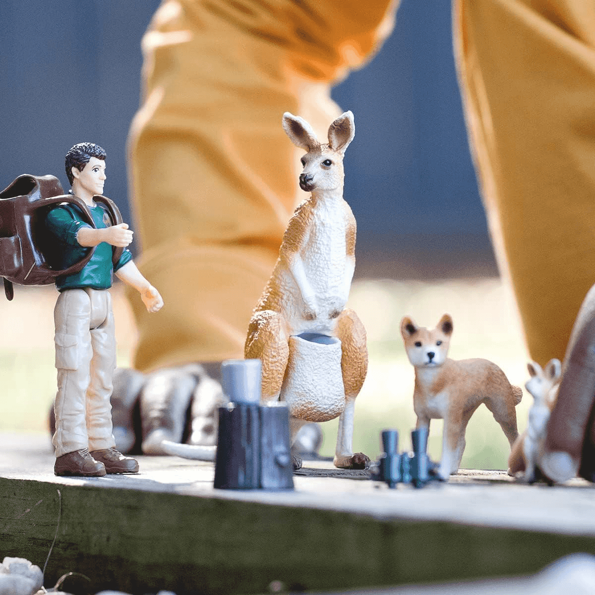 Figurines miniatures d'un randonneur, d'un kangourou et d'un chien sur une surface en bois.