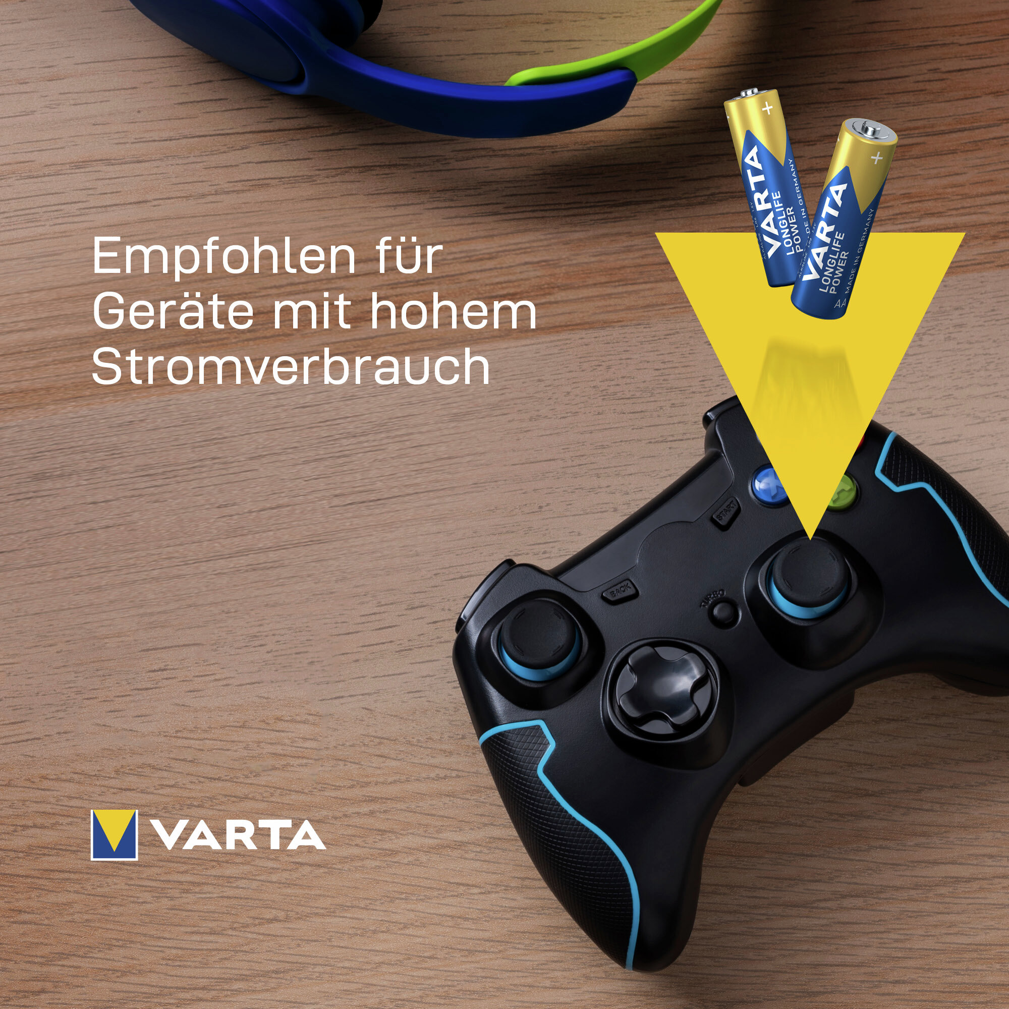 Due batterie Varta e un controller di gioco nero su un tavolo di legno.