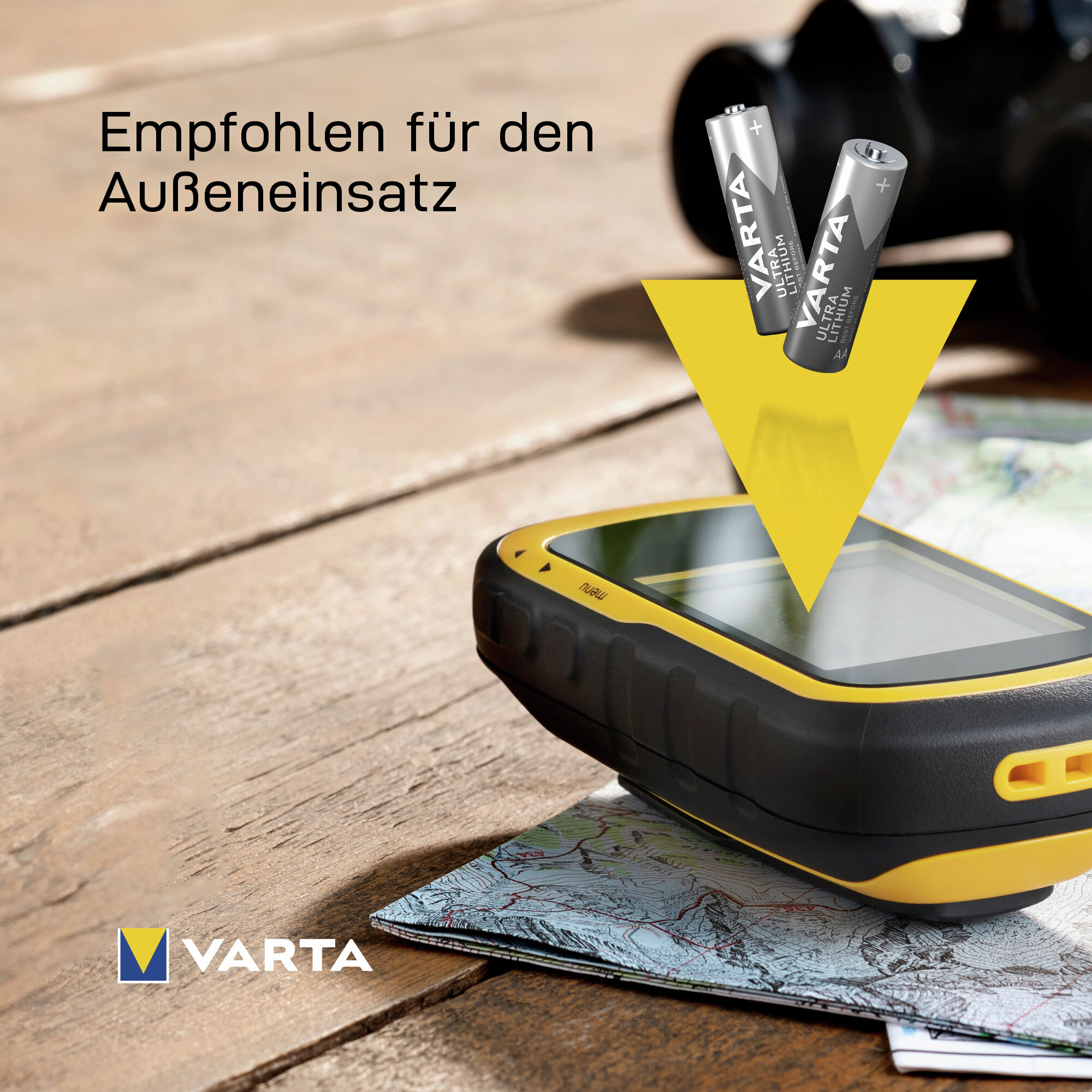 Dos pilas Varta AA flotan sobre un dispositivo GPS y un mapa en una superficie de madera.