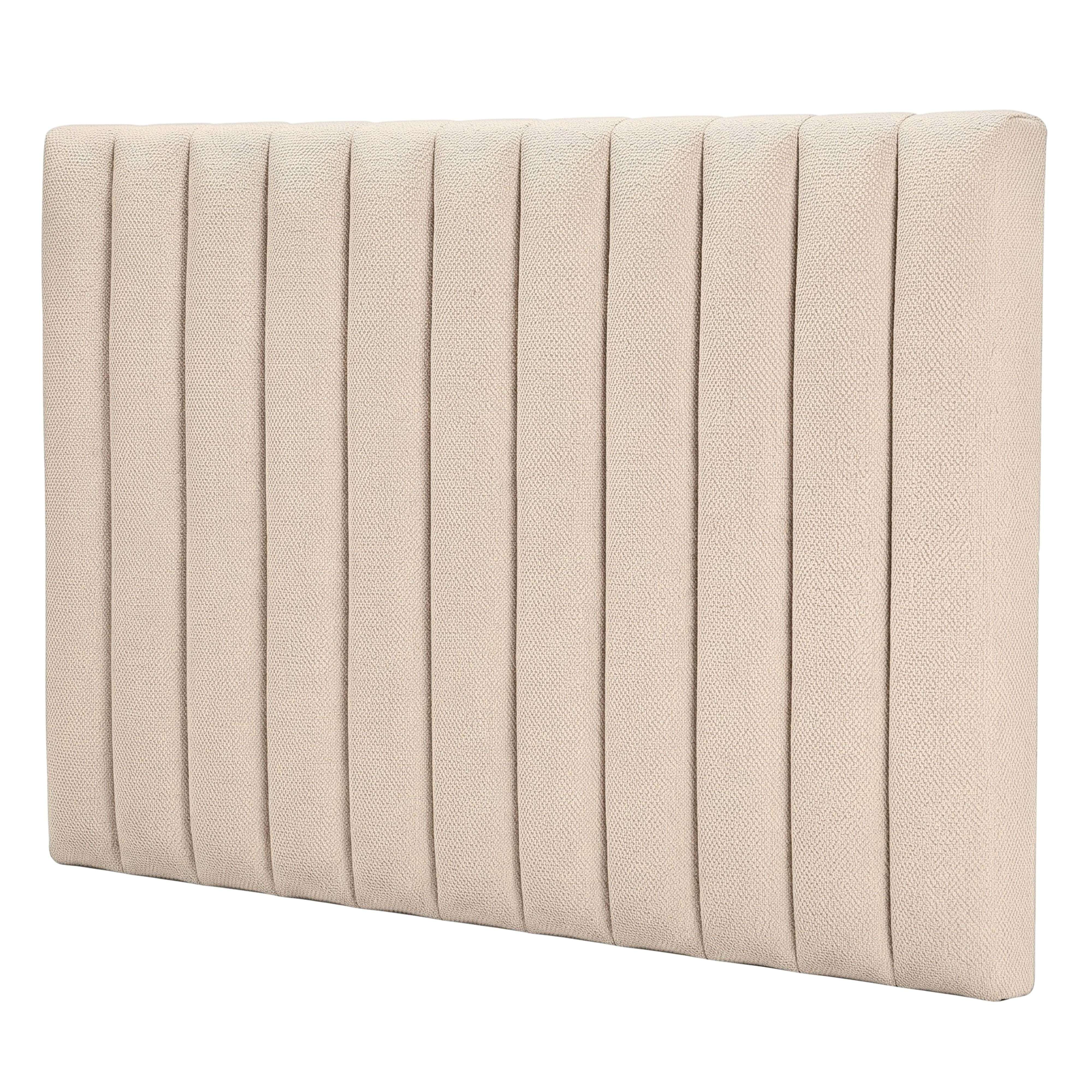 Un cabecero de cama tapizado en beige con paneles verticales acolchados sobre fondo blanco.