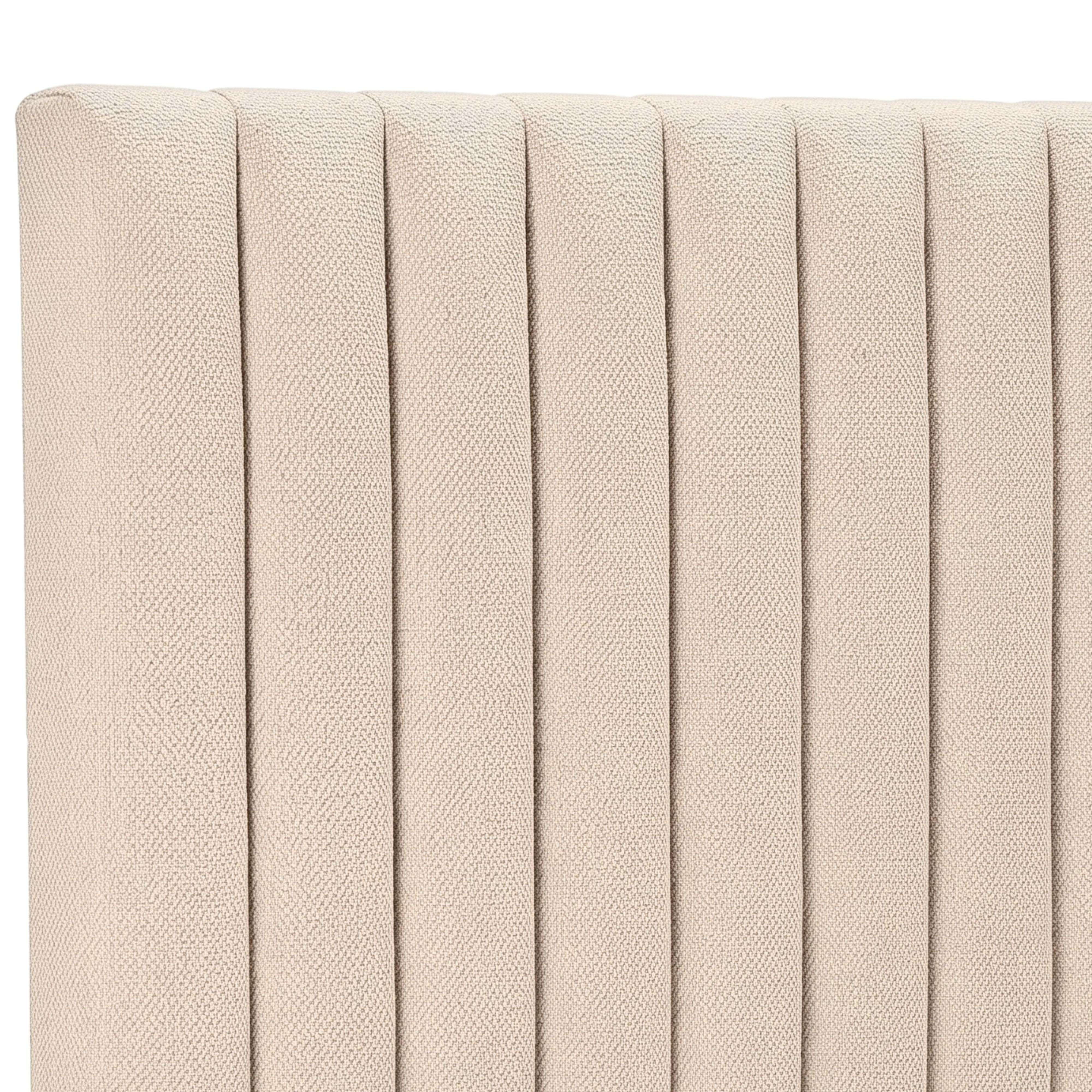 Un cabecero tapizado de color beige claro con costuras verticales.