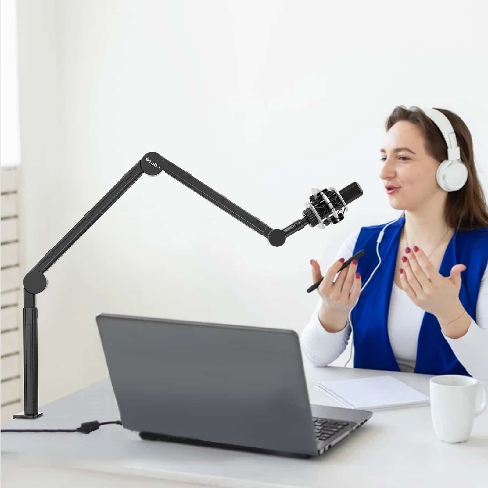 Femme avec casque parle devant un ordinateur portable, un bras de micro sur le bureau.