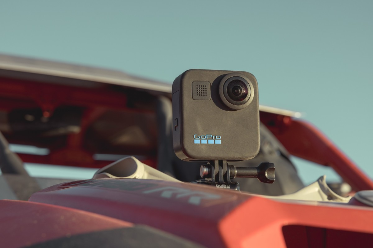 Una telecamera GoPro nera è montata sul cofano rosso di un fuoristrada.