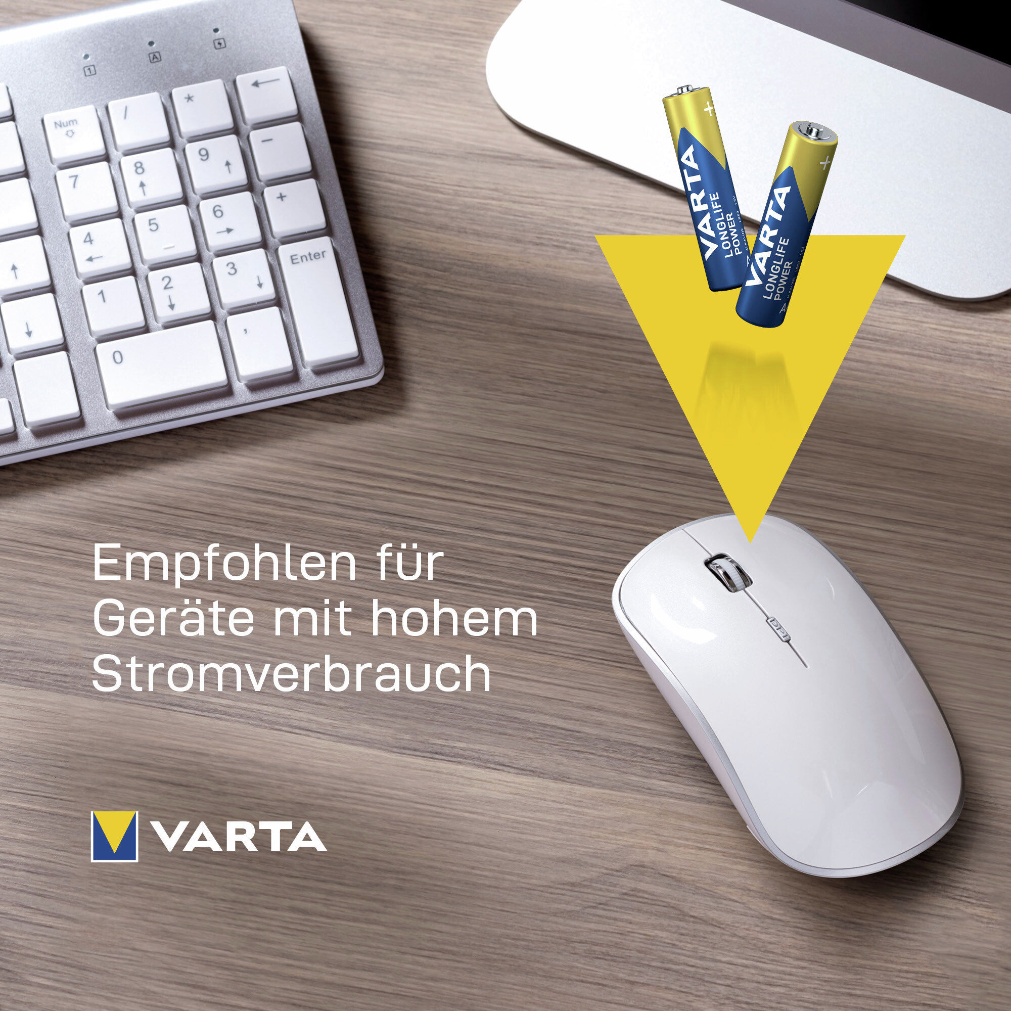 Due batterie Varta illuminano con un raggio giallo un mouse bianco su una scrivania in legno.
