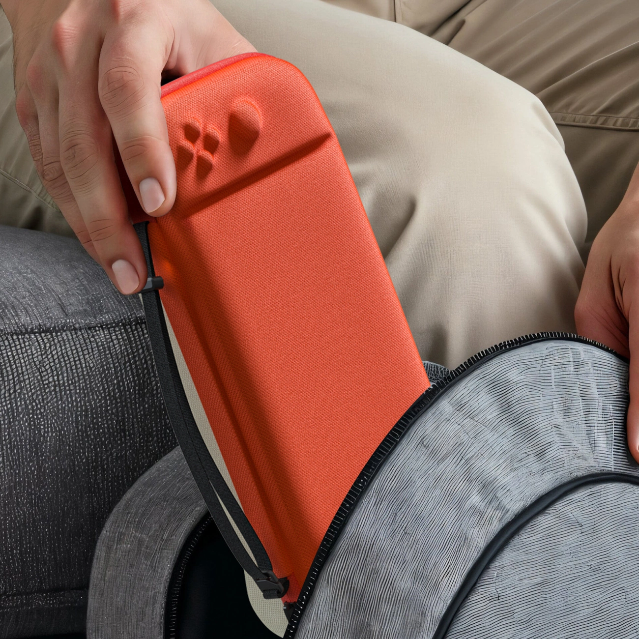 Una persona ripone una custodia arancione brillante per console in una borsa.