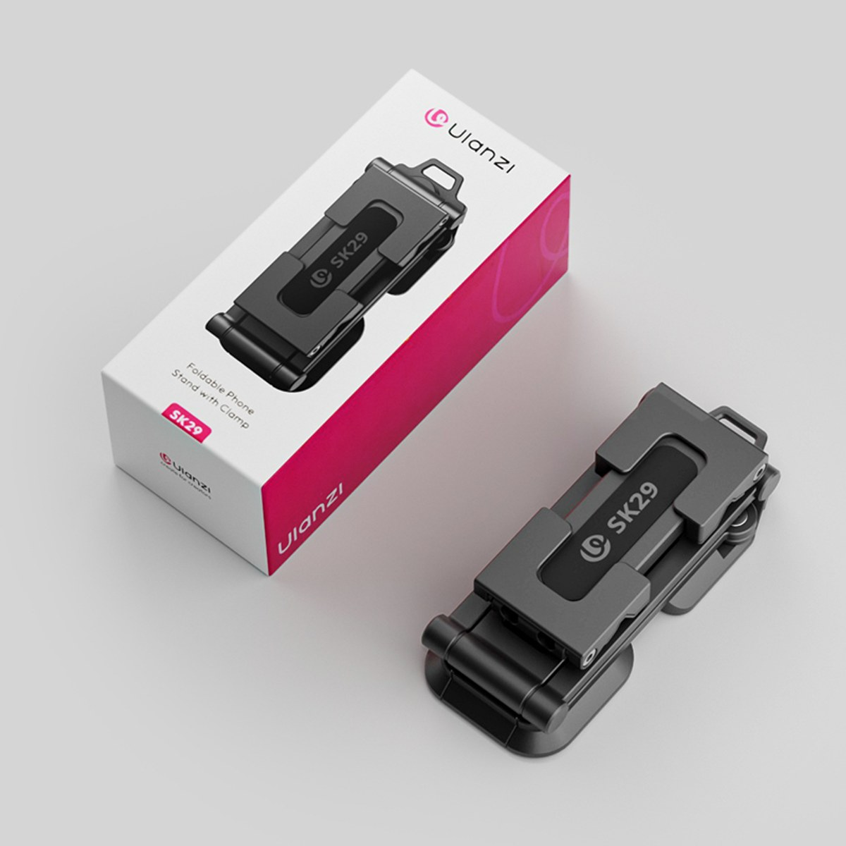Ein Ulanzi SK29 faltbarer Handyhalter mit Klemme liegt neben seiner weiß-pinken Produktverpackung.