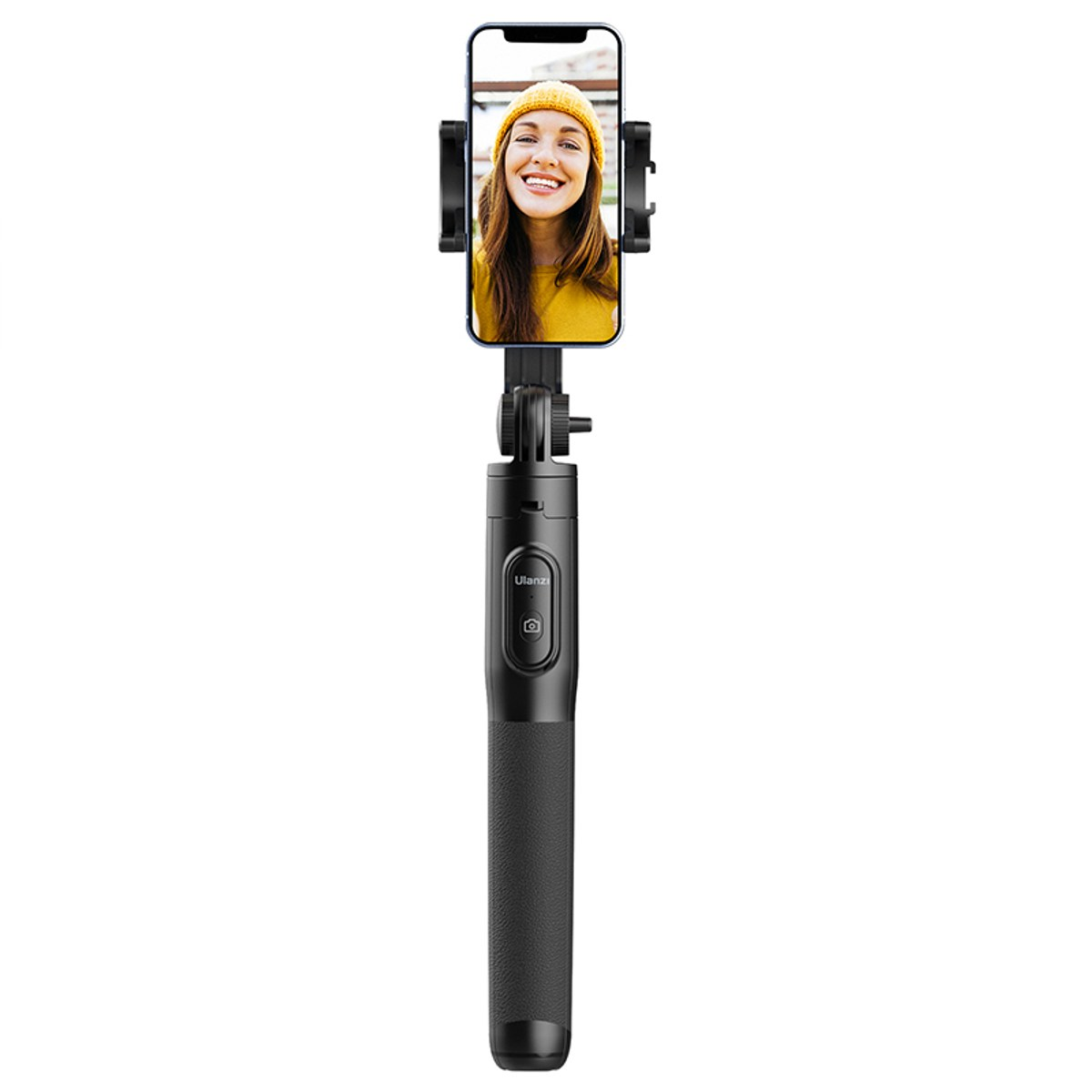 Un selfie stick noir tient un smartphone affichant la photo d'une femme souriante avec un bonnet jaune.