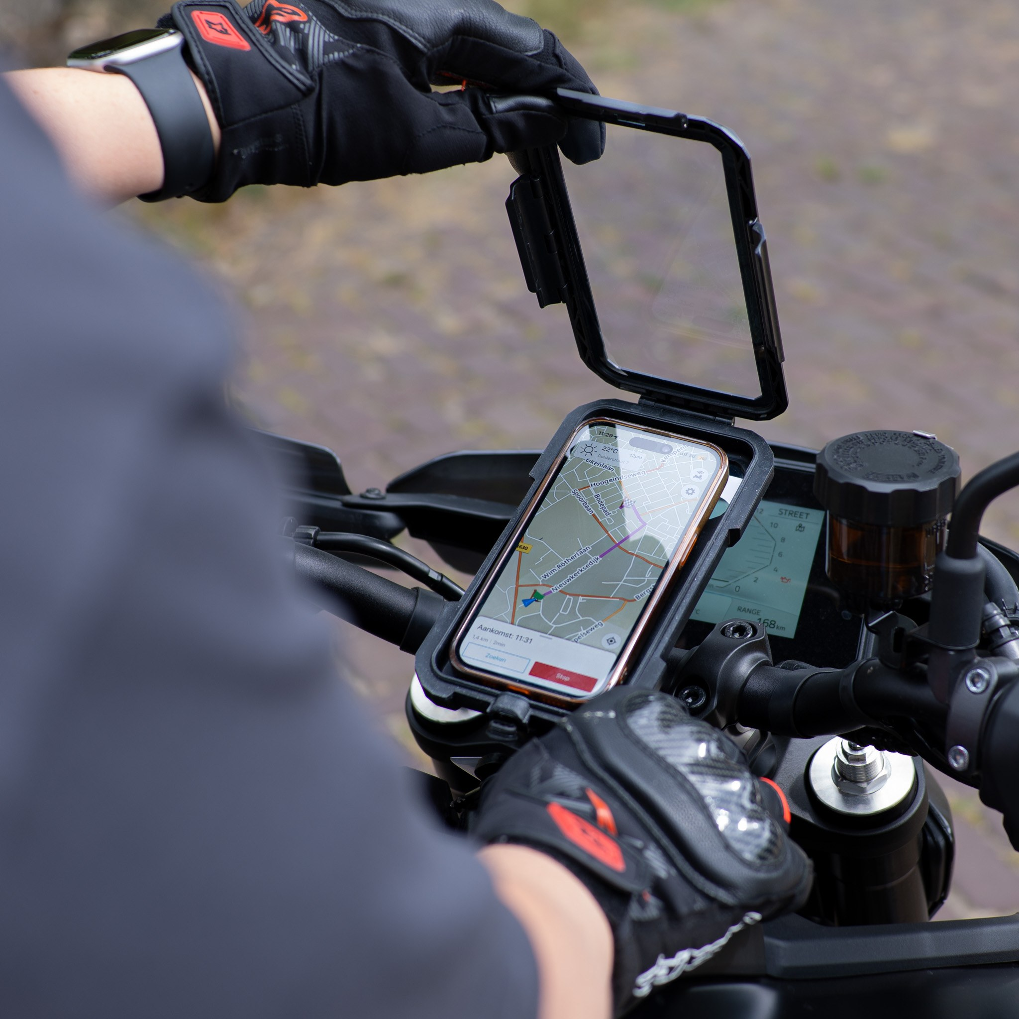 Un motard ouvre un support de smartphone sur le guidon avec une carte GPS sur l'écran.
