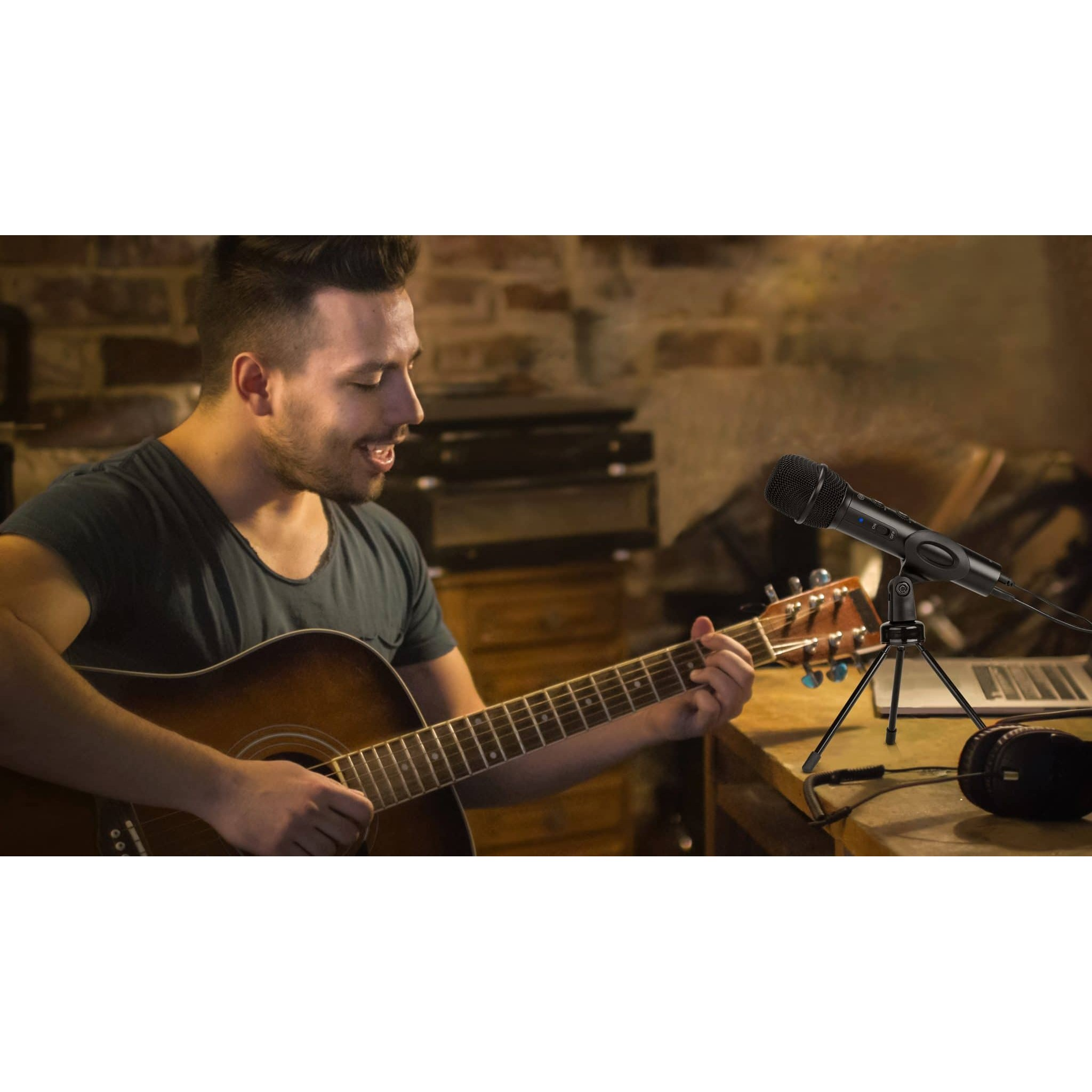 Ein Mann spielt Akustikgitarre mit einem schwarzen Mikrofon auf einem Stativ im Vordergrund.