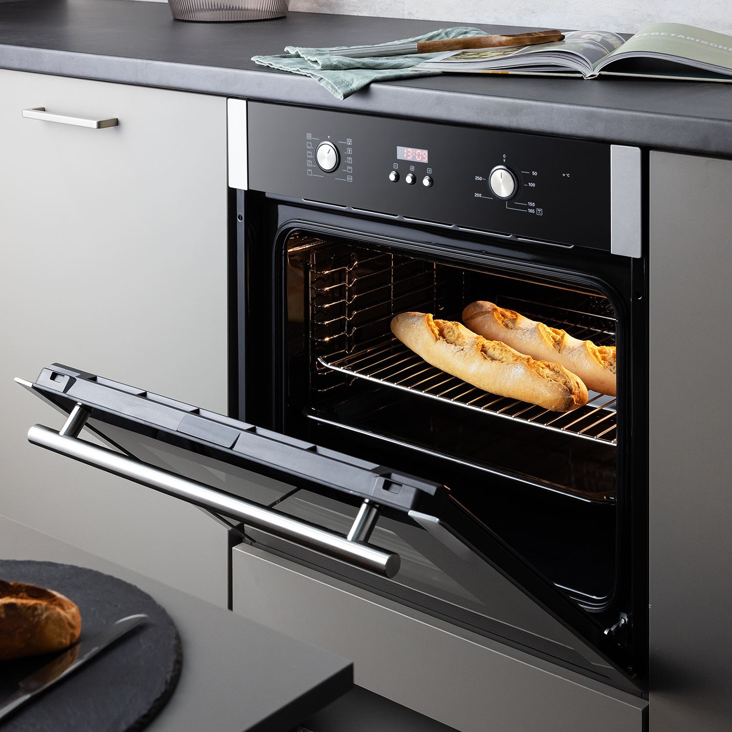 Zwei Baguettes backen im offenen Einbauofen in einer modernen Küche.