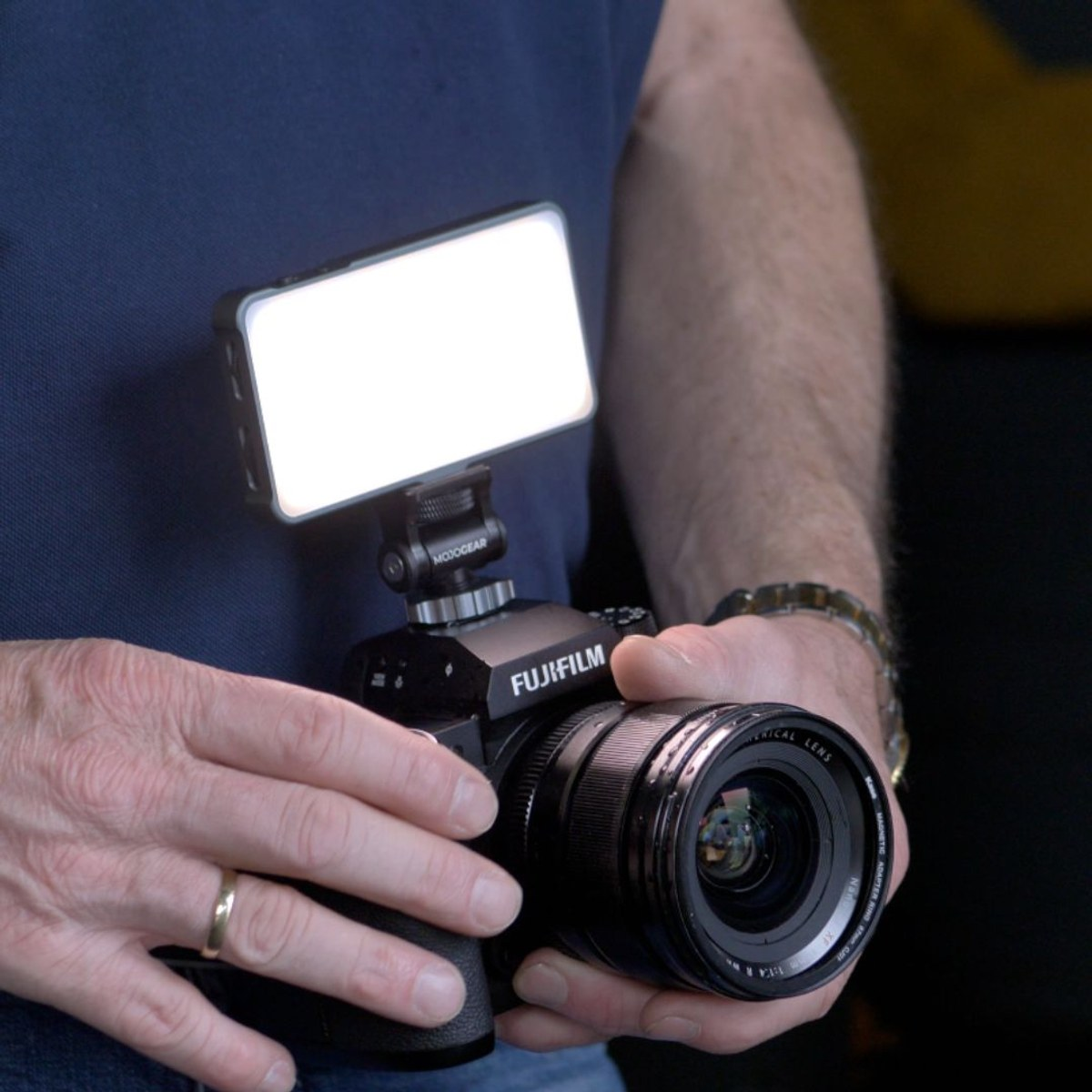 Handen houden een Fujifilm-camera vast met een bevestigd led-lampje.