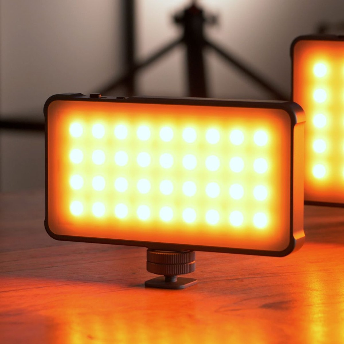 Twee draagbare LED-panelen die helder, warm licht uitstralen op een houten tafel.