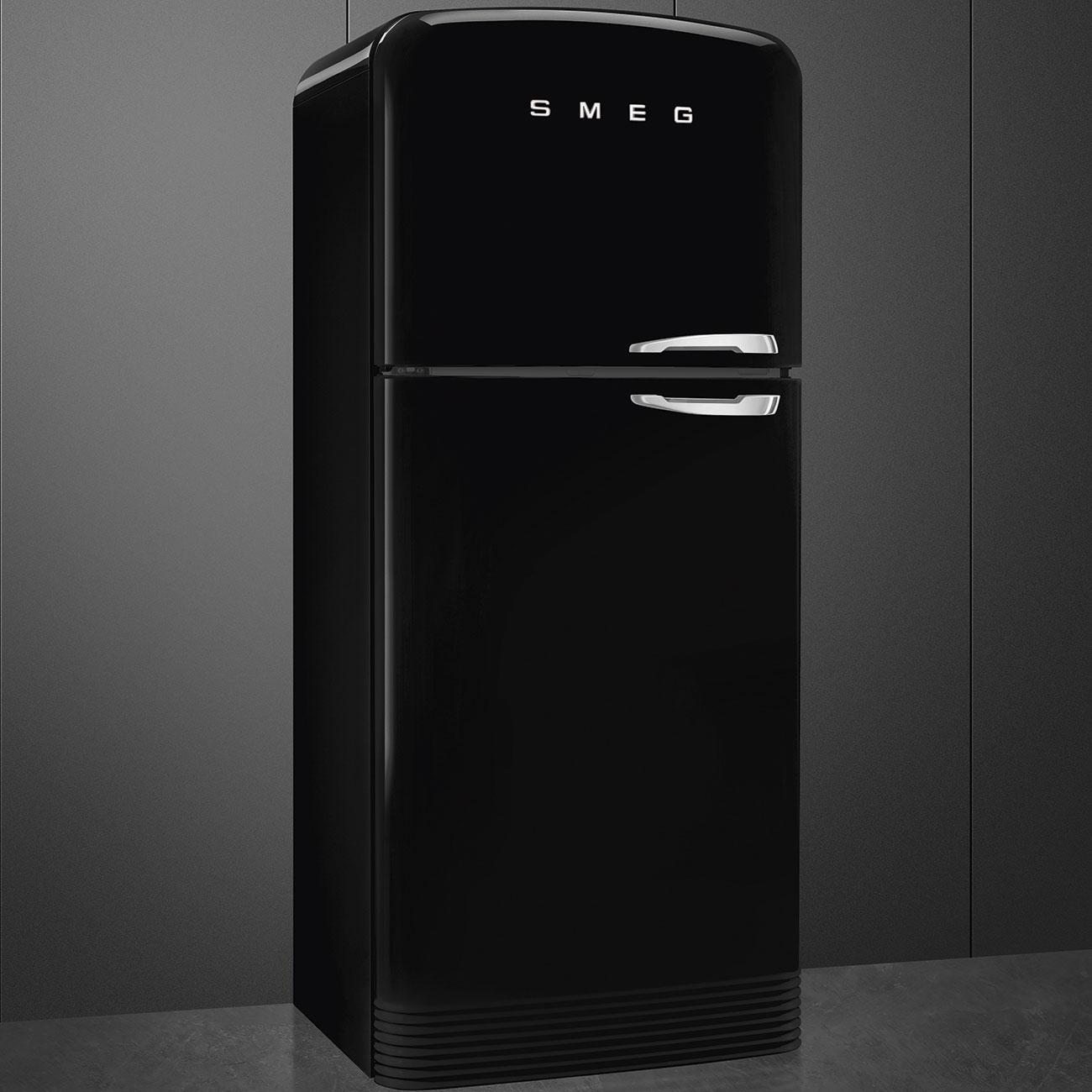 Un refrigerador Smeg negro brillante se encuentra en una cocina oscura contra una pared gris.