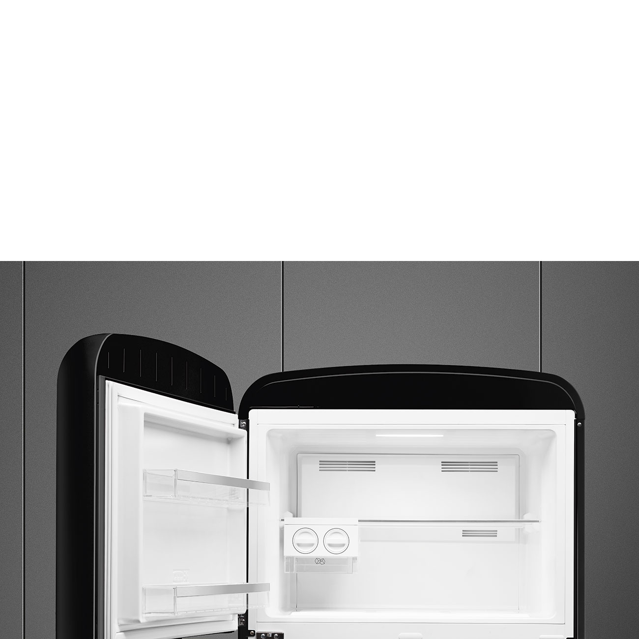Un refrigerador negro abierto con interior blanco y estantes vacíos contra una pared de azulejos grises.