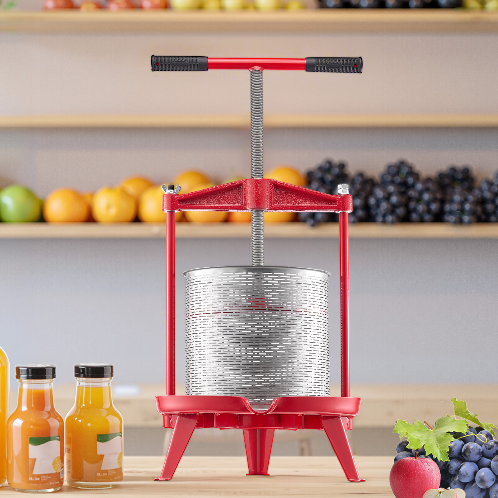 Una prensa de frutas roja sobre una mesa frente a estantes con fruta fresca y zumo.