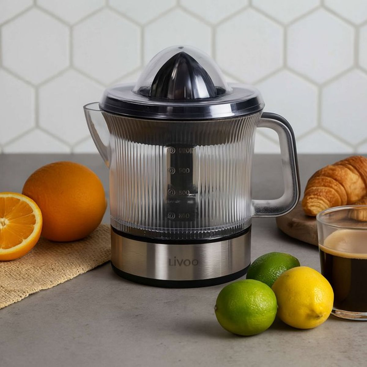 Spremiagrumi elettrico con arance, lime e un croissant sul bancone.