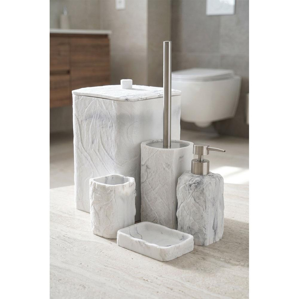 Açık yüzey üzerinde beyaz mermer banyo aksesuar seti; sabunluk, bardak, sabunluk tabağı ve çöp kutusu içerir.