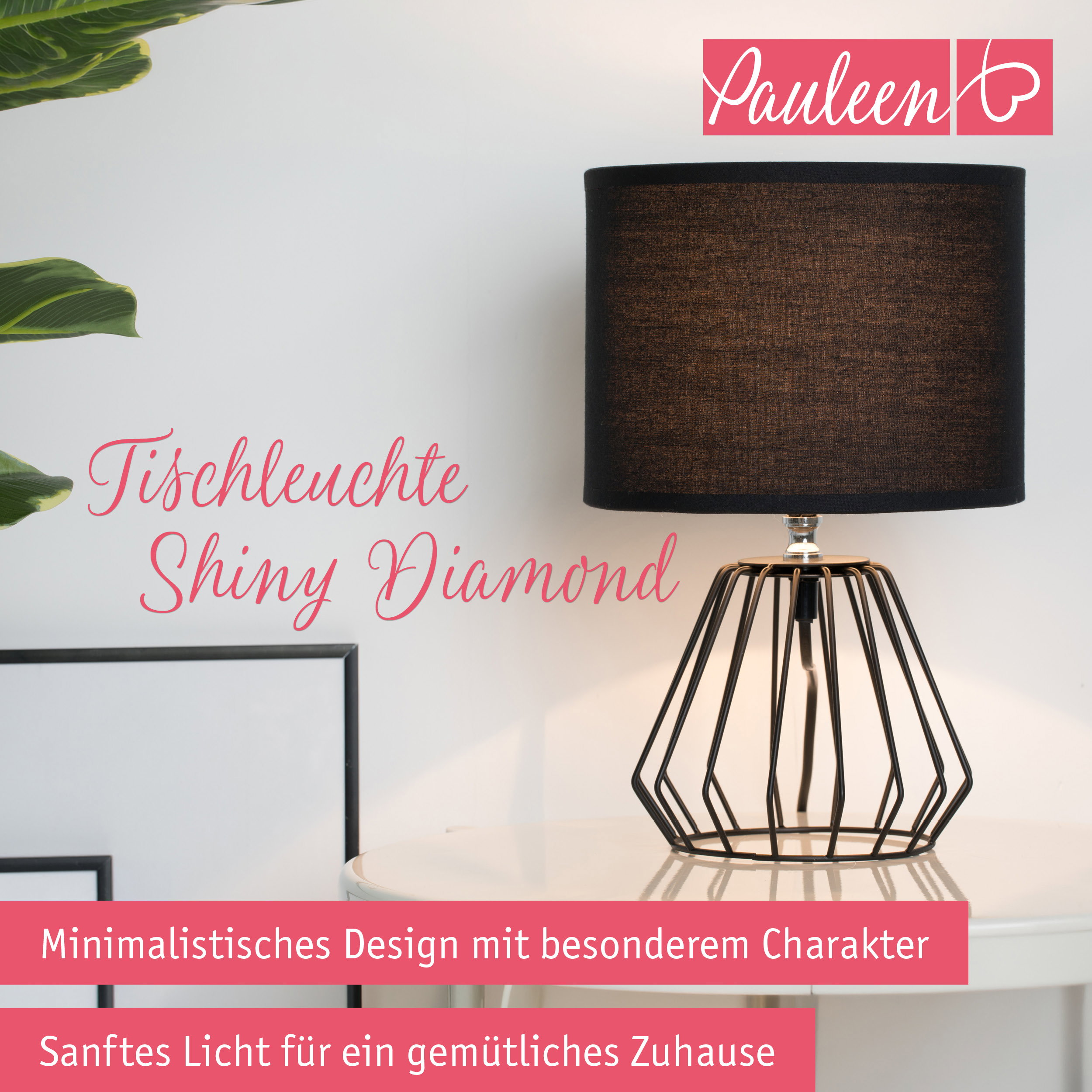 Eine schwarze Tischlampe mit geometrischem Drahtfuß und schwarzem Schirm steht auf einem weißen Tisch.