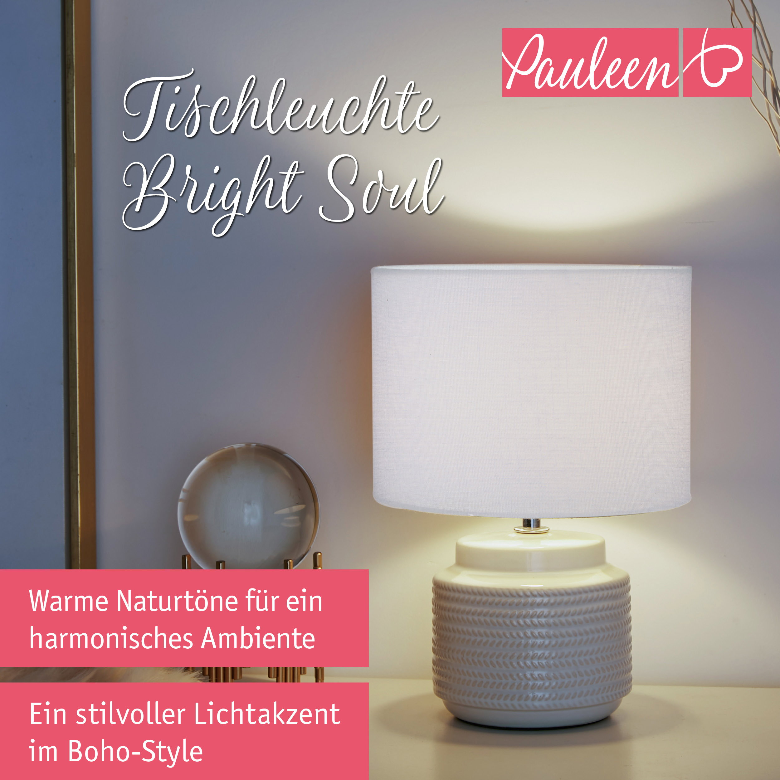 Beige Tischleuchte mit weißem Schirm und Muster auf einem Tisch mit Deko.