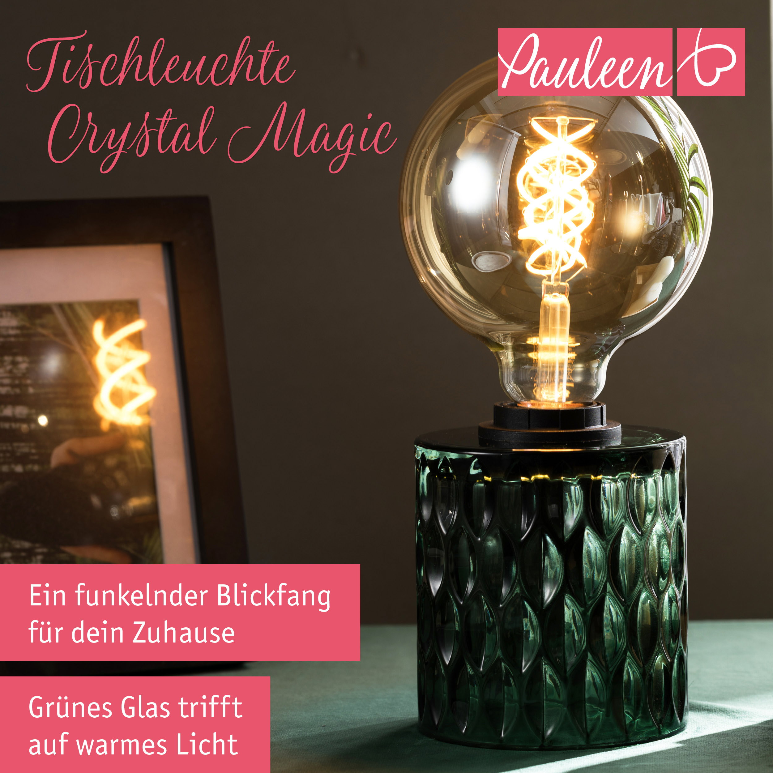 Una lampada da tavolo in vetro verde con una grande lampadina rotonda e luce calda su un tavolo.