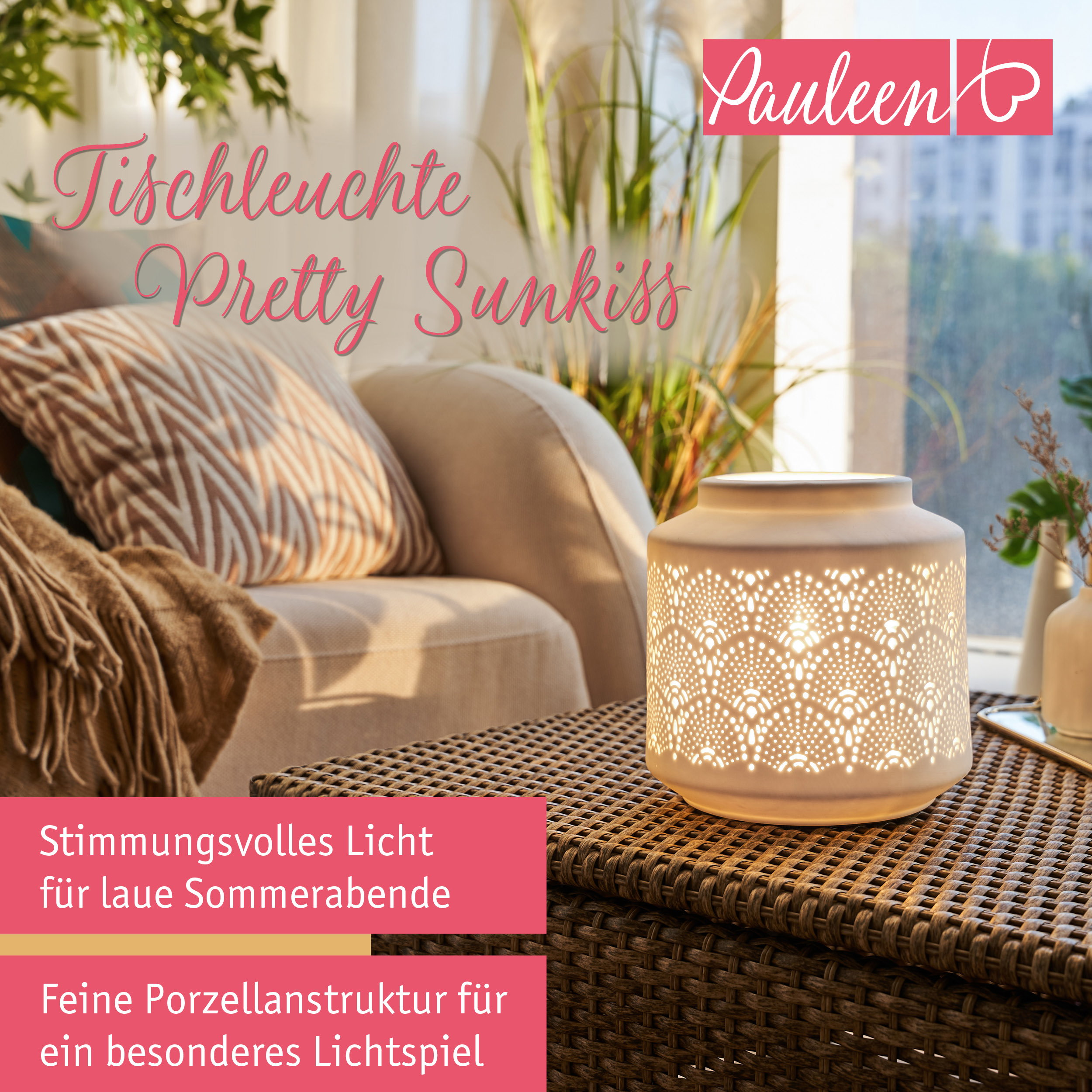 Beleuchtete Tischleuchte mit Porzellanmuster auf einem Rattantisch, mit Kissen und Pflanzen im Hintergrund.