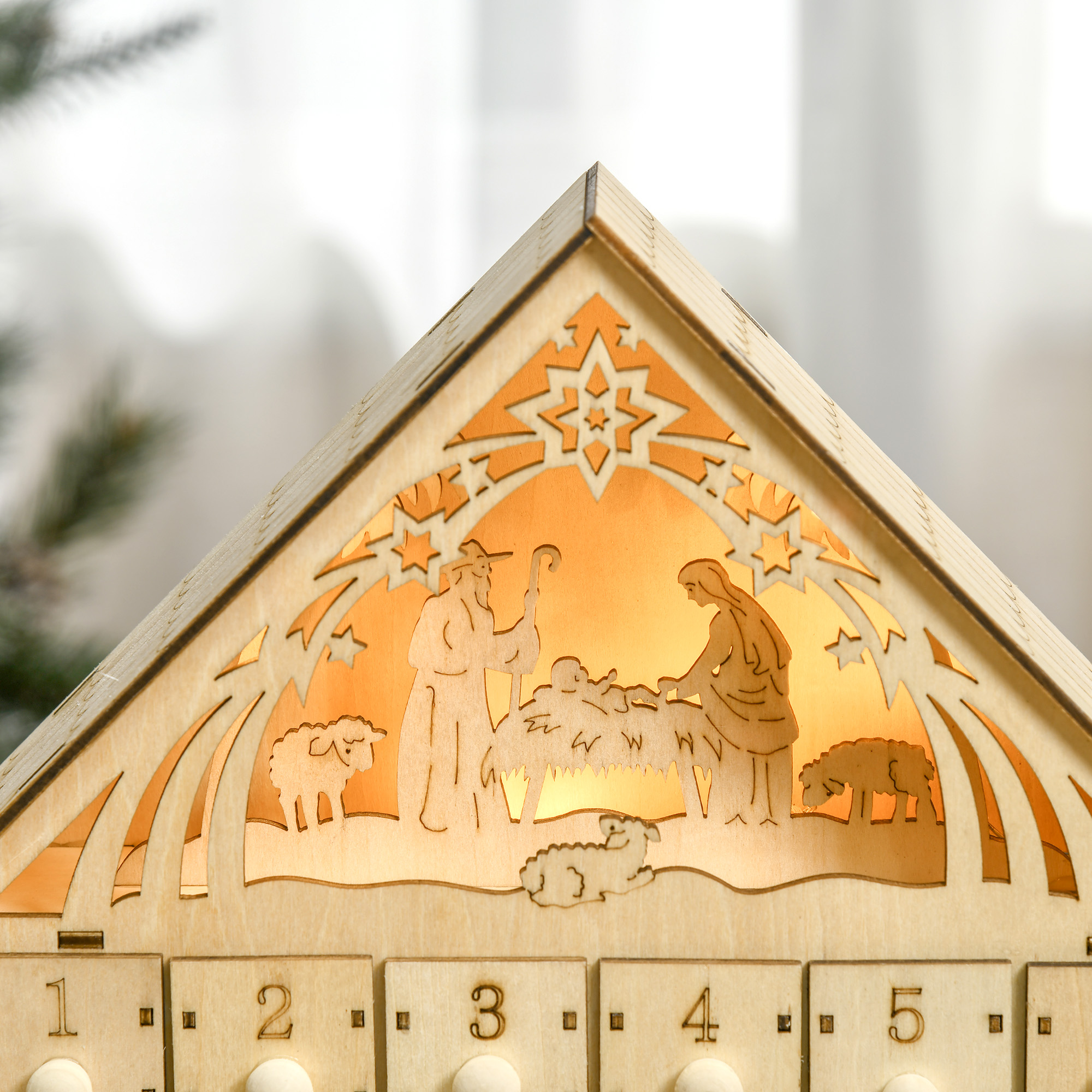 Escena de belén de madera iluminada con figuras y cajones numerados.