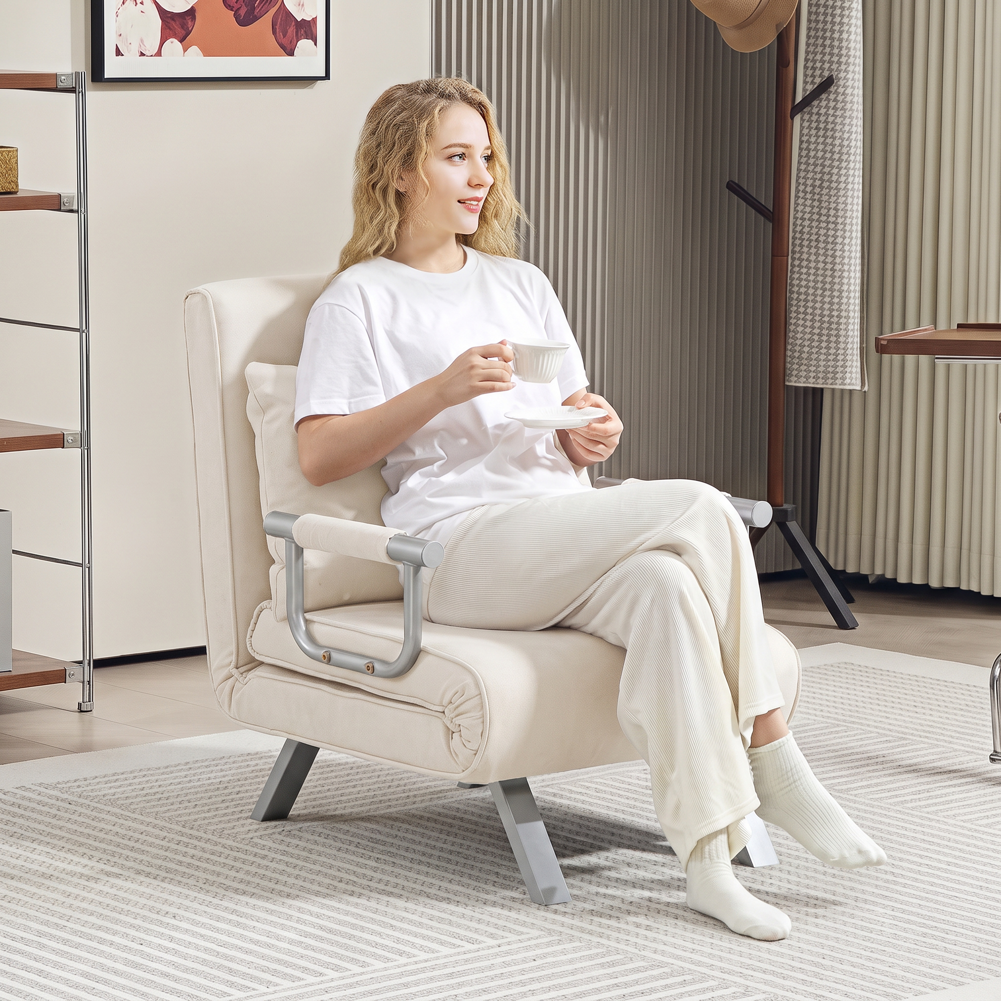 Una mujer rubia se sienta en un sillón claro en una habitación moderna, sosteniendo una taza de café.