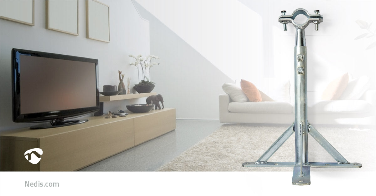 Metallmast mit dreibeiniger Halterung im Vordergrund, im Hintergrund ein helles Wohnzimmer mit Fernseher.