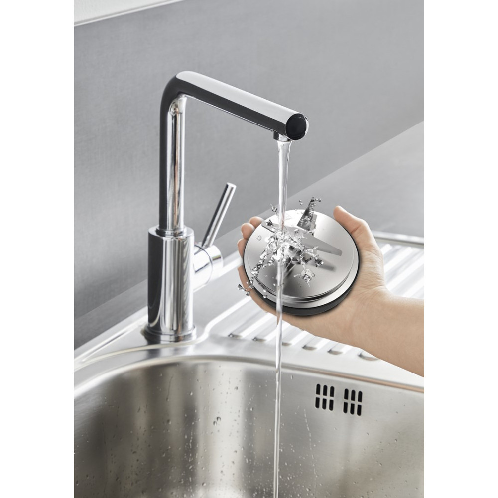 Eine Hand hält einen Mixeraufsatz unter fließendes Wasser in einer Edelstahlspüle.