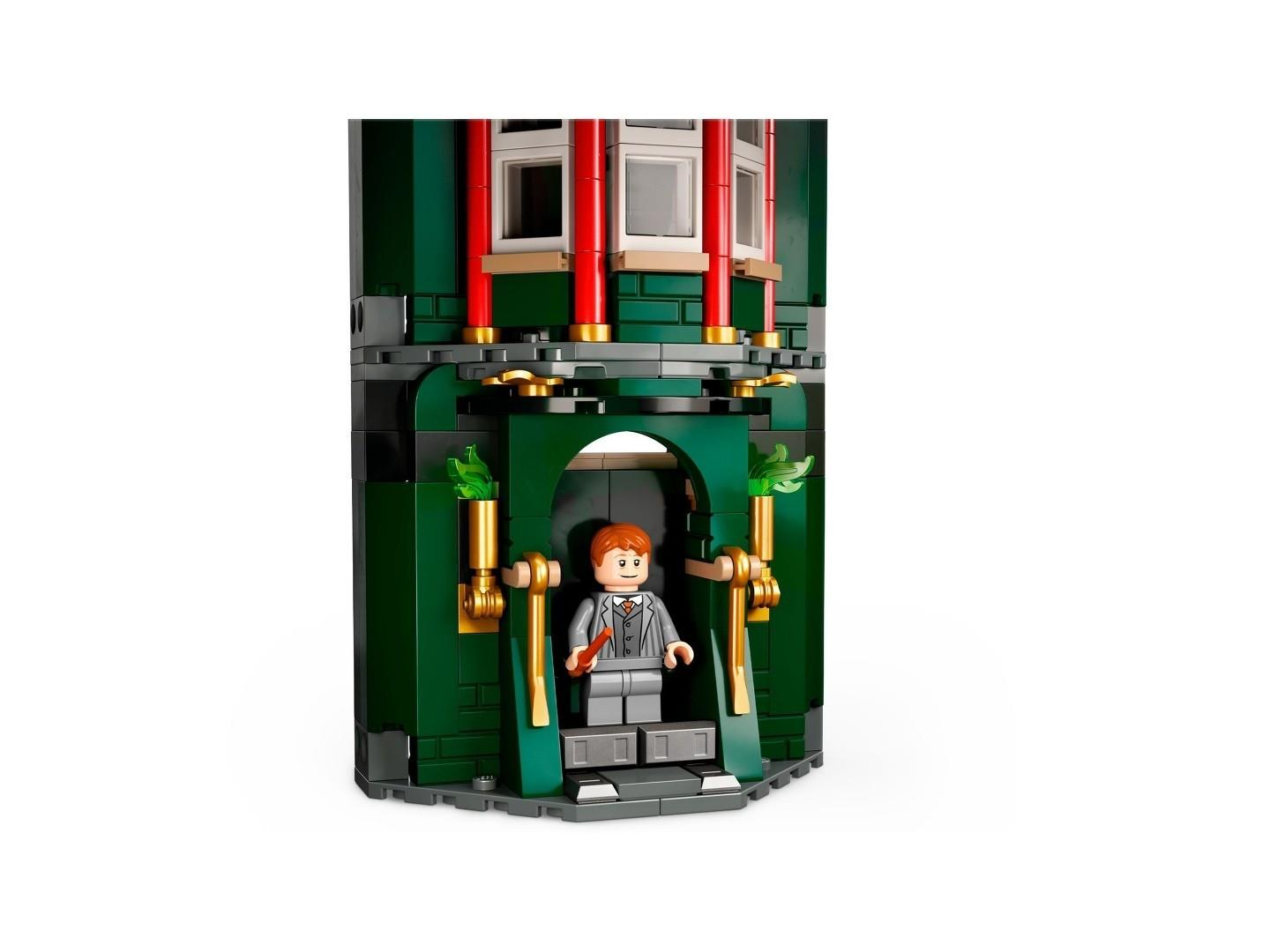 Lego-Figur in einem grauen Anzug steht im Eingang eines grünen Lego-Gebäudes mit roten Säulen.