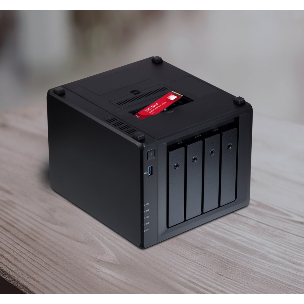 Un dispositivo NAS negro con cuatro bahías y una SSD roja en la ranura superior sobre una mesa de madera.