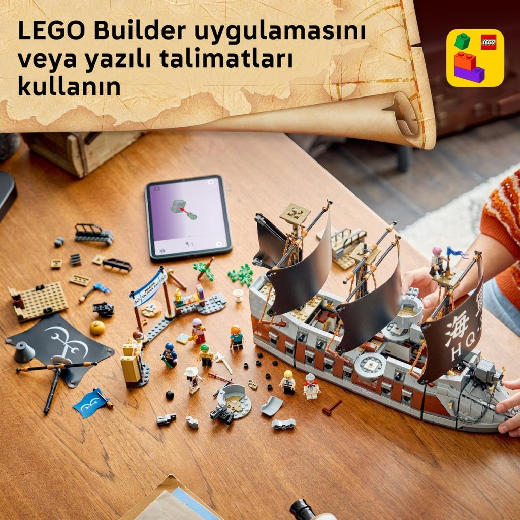 Bir kişi ahşap masada, minifigürler ve talimatları gösteren bir tablet eşliğinde büyük bir LEGO korsan gemisi kuruyor.