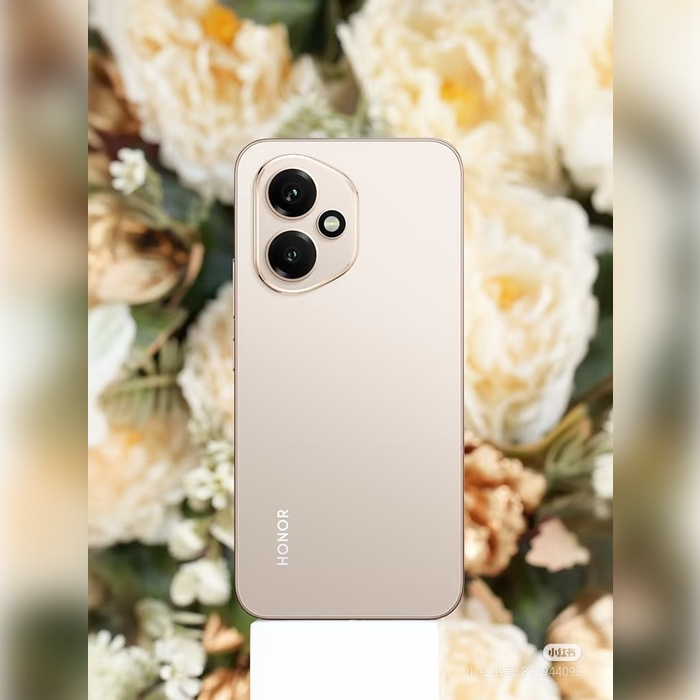 Ein goldenes Honor-Smartphone steht auf einem Sockel vor einem weichen Hintergrund aus weißen und beigen Blumen.