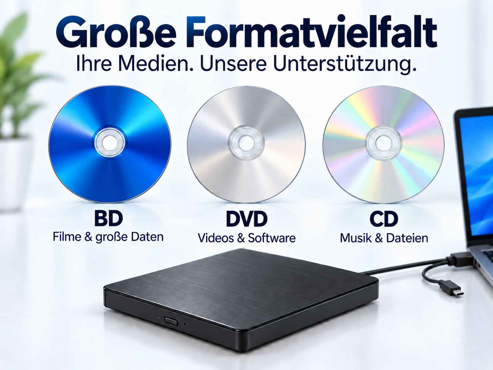 Blaue Blu-ray, silberne DVD und CD über einem externen schwarzen Laufwerk und Laptop.