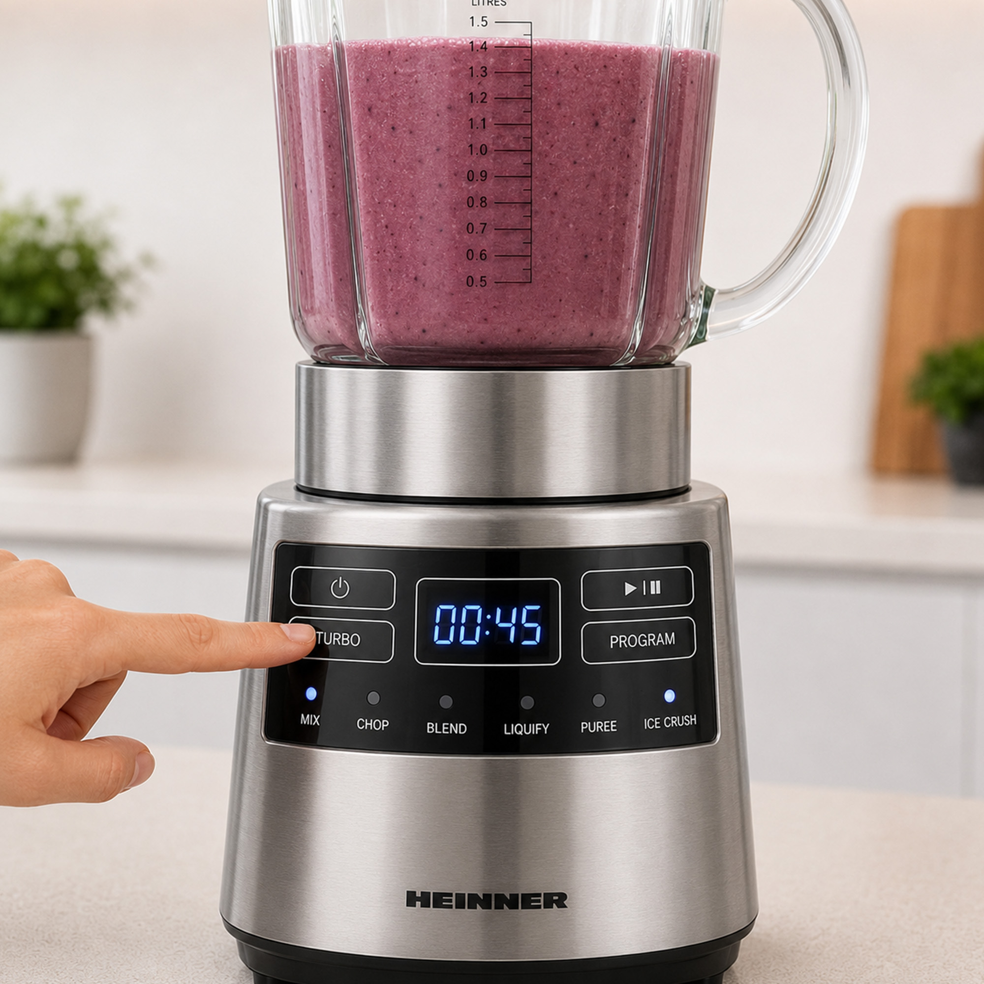 Un doigt appuie sur le bouton turbo d'un blender en acier inoxydable rempli de smoothie.