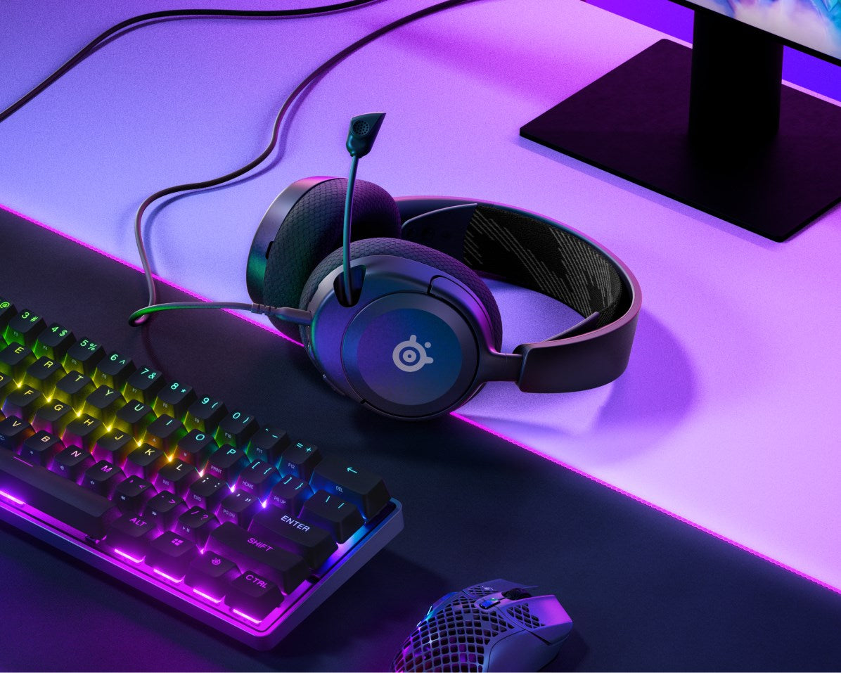 Gaming headset, illuminated keyboard, and mouse on a purple and black desk mat.