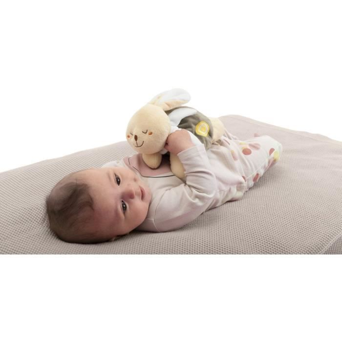 Un neonato sdraiato su una coperta chiara stringe un peluche.
