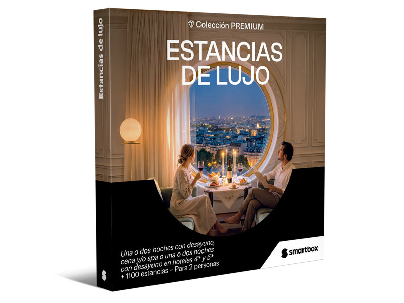 Caja de lujo con pareja cenando junto a un gran ventanal circular con vistas a la ciudad iluminada.