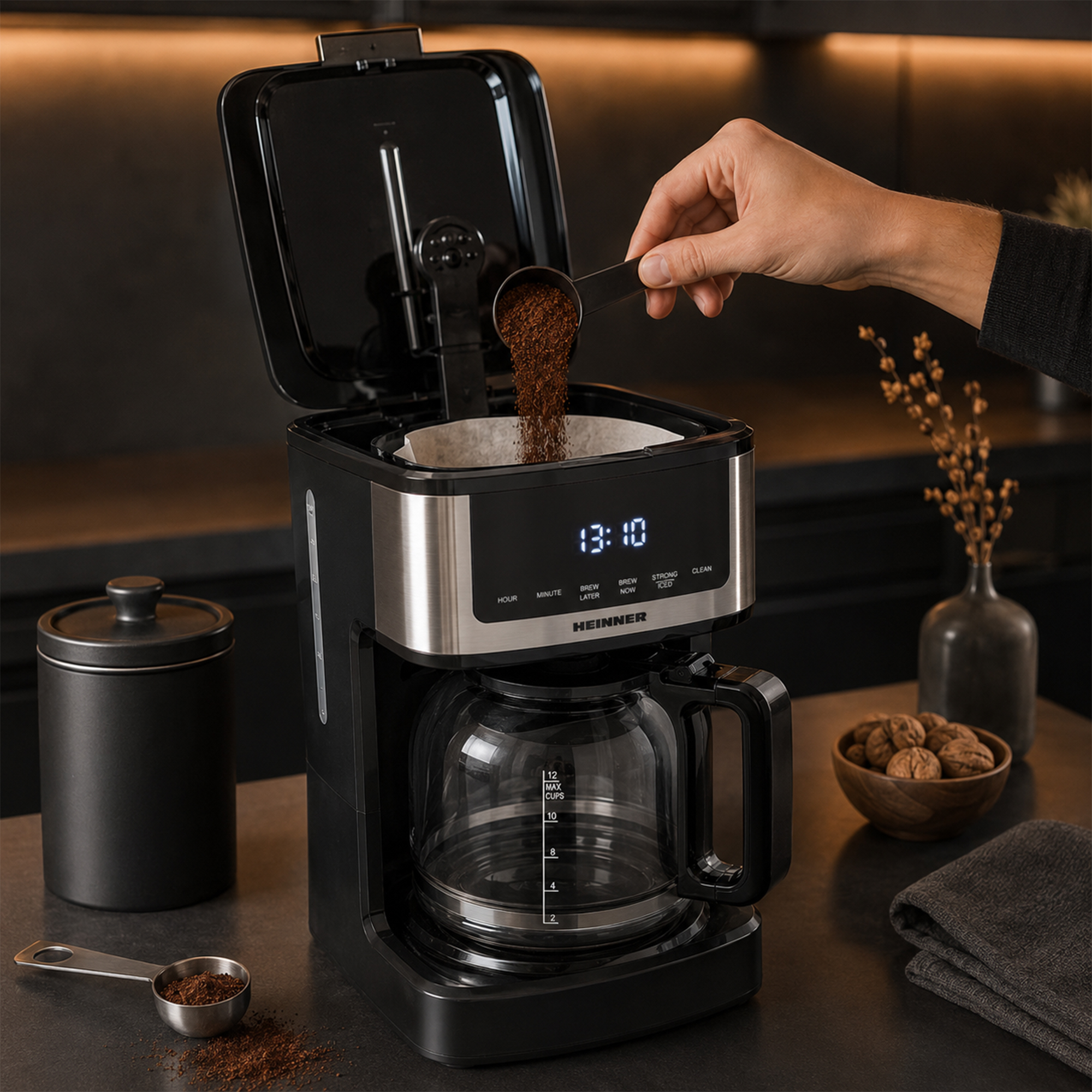 Een hand giet gemalen koffie uit een schepje in het filter van een koffiezetapparaat.