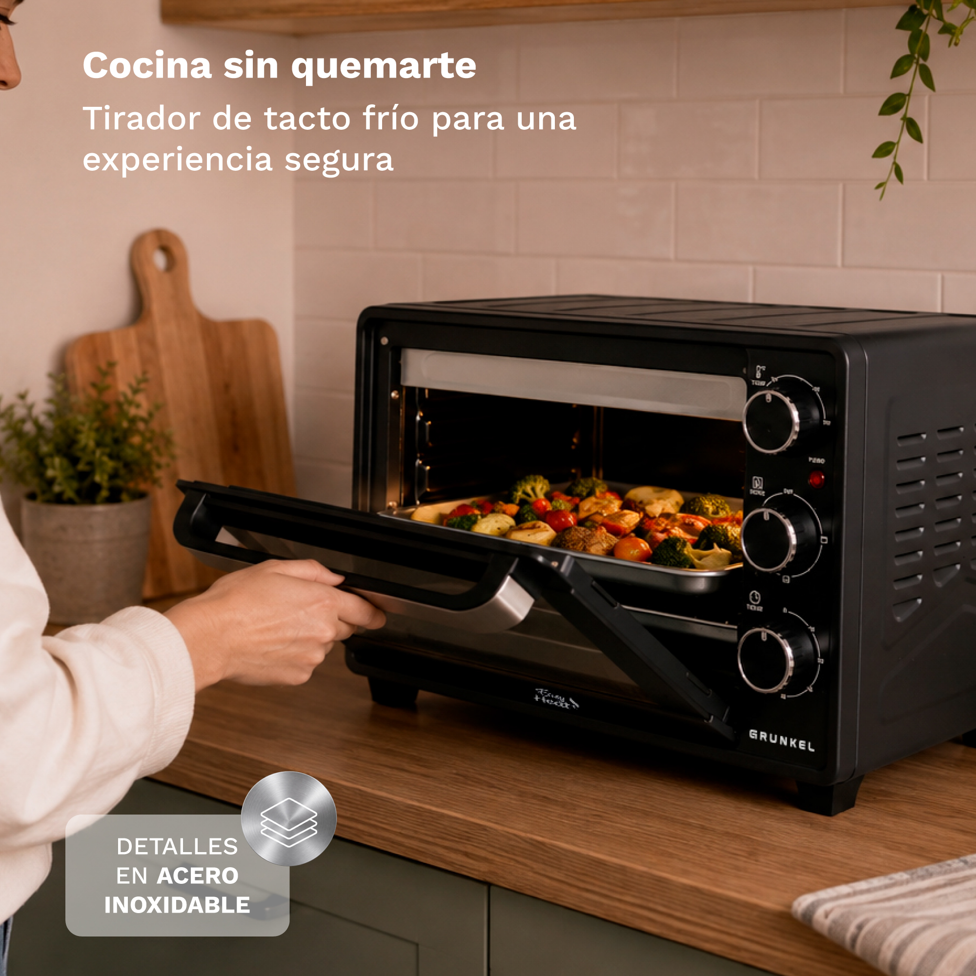 Mano abriendo horno negro con bandeja de verduras en encimera.