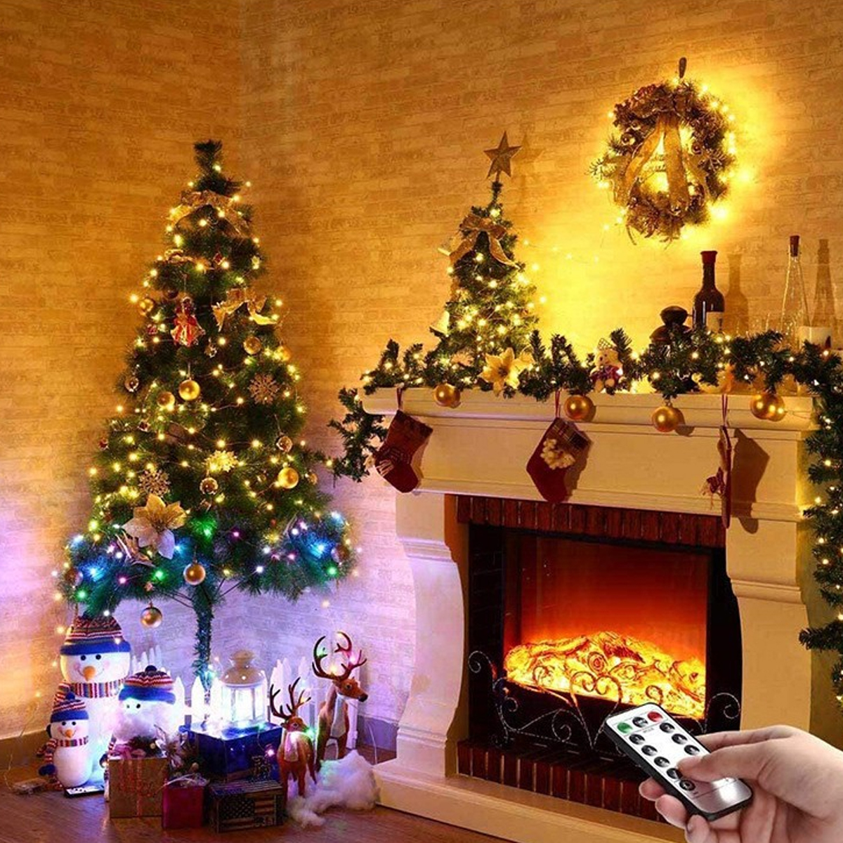 Beleuchteter Weihnachtsbaum, Kamin mit Lichtern, Girlanden und Dekorationen sowie eine Hand mit Fernbedienung.