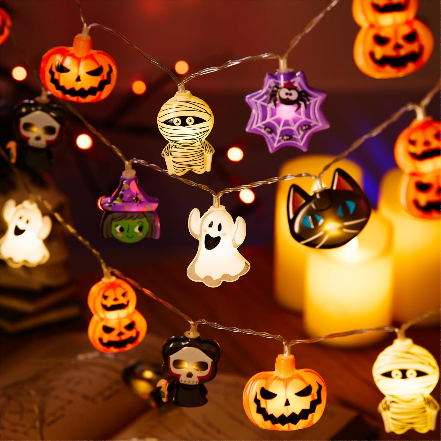 Halloween-Lichterkette mit leuchtenden Kürbissen, Mumien, Geistern, Hexen und Katzen vor dunklem Hintergrund.
