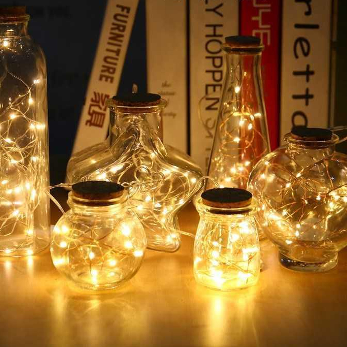 Mehrere Glasflaschen und Gläser mit Korken gefüllt mit hellen Lichterketten.