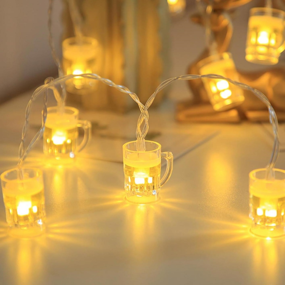 Eine leuchtende Lichterkette mit Miniatur-Bierkrügen auf einem weißen Tisch.