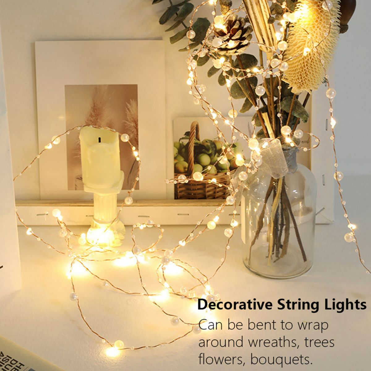 Dekorative Lichterkette mit weißen Perlen und warm leuchtenden LEDs liegt auf einem Tisch.