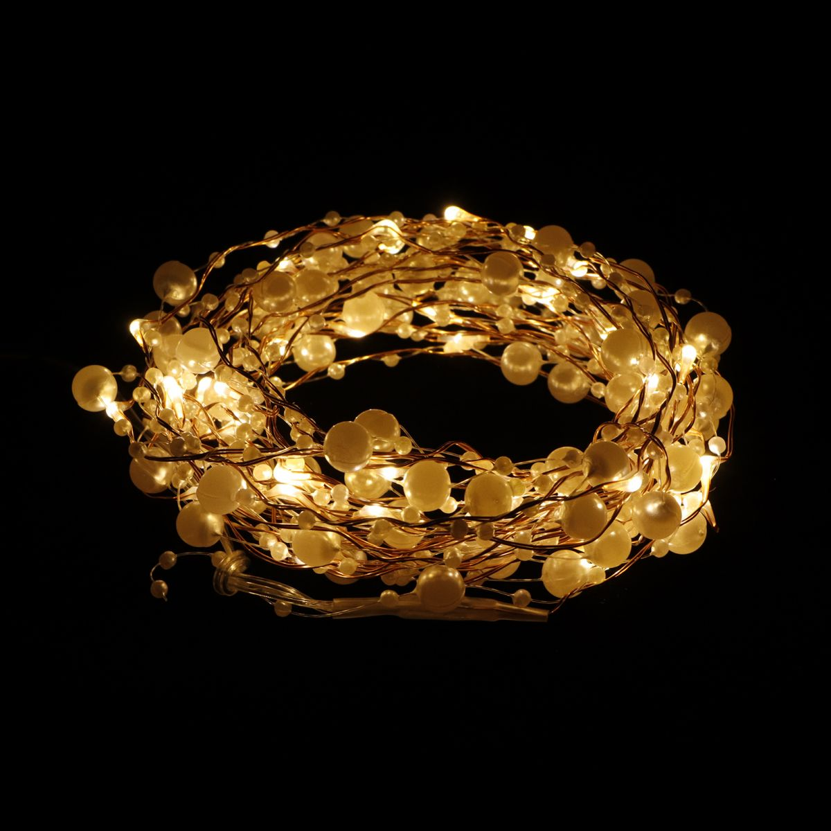 Eine spiralförmige Lichterkette mit weißen Perlen und warmem LED-Licht leuchtet vor einem schwarzen Hintergrund.