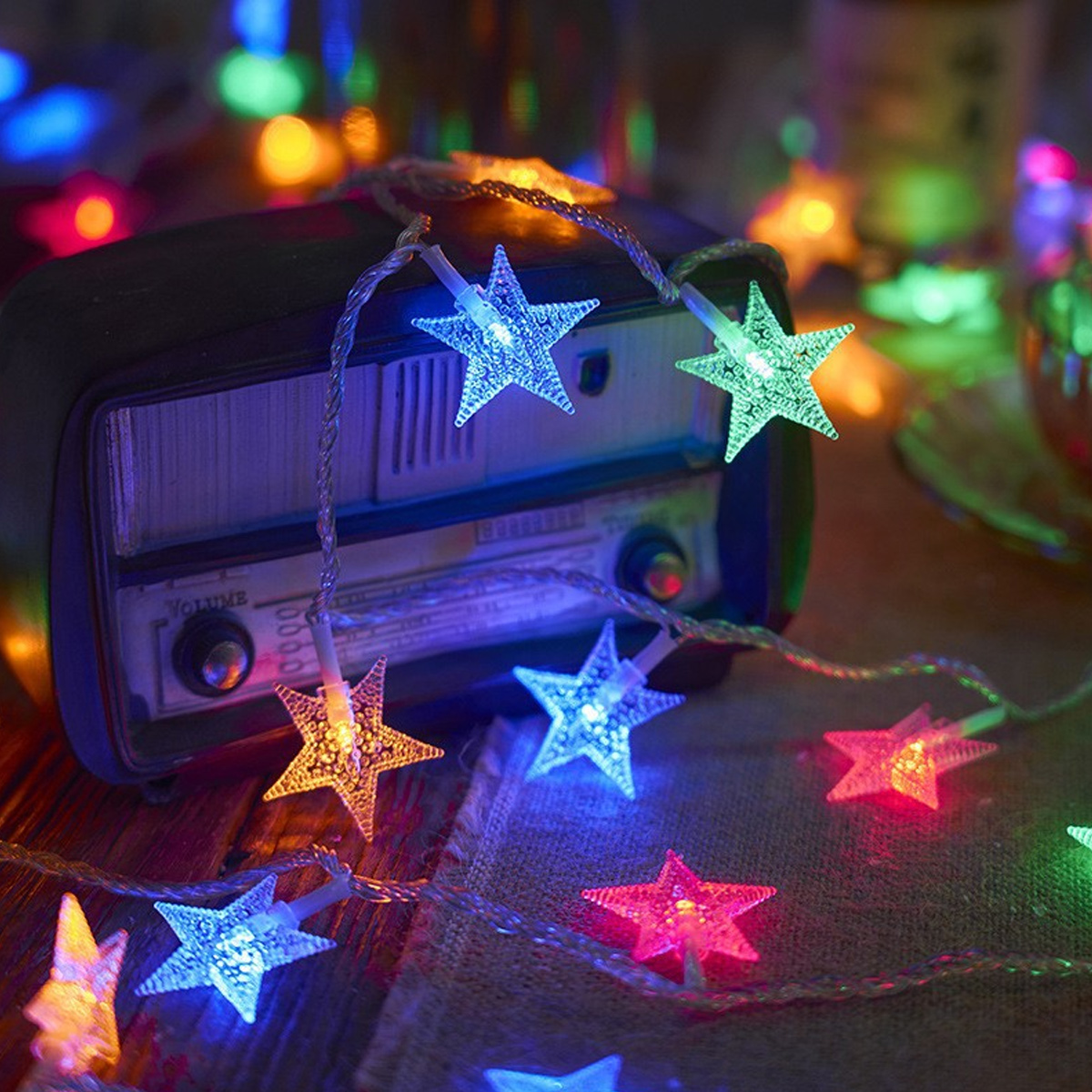 Bunt leuchtende sternförmige Lichterkette über einem Vintage-Radio in einem gemütlichen Raum.
