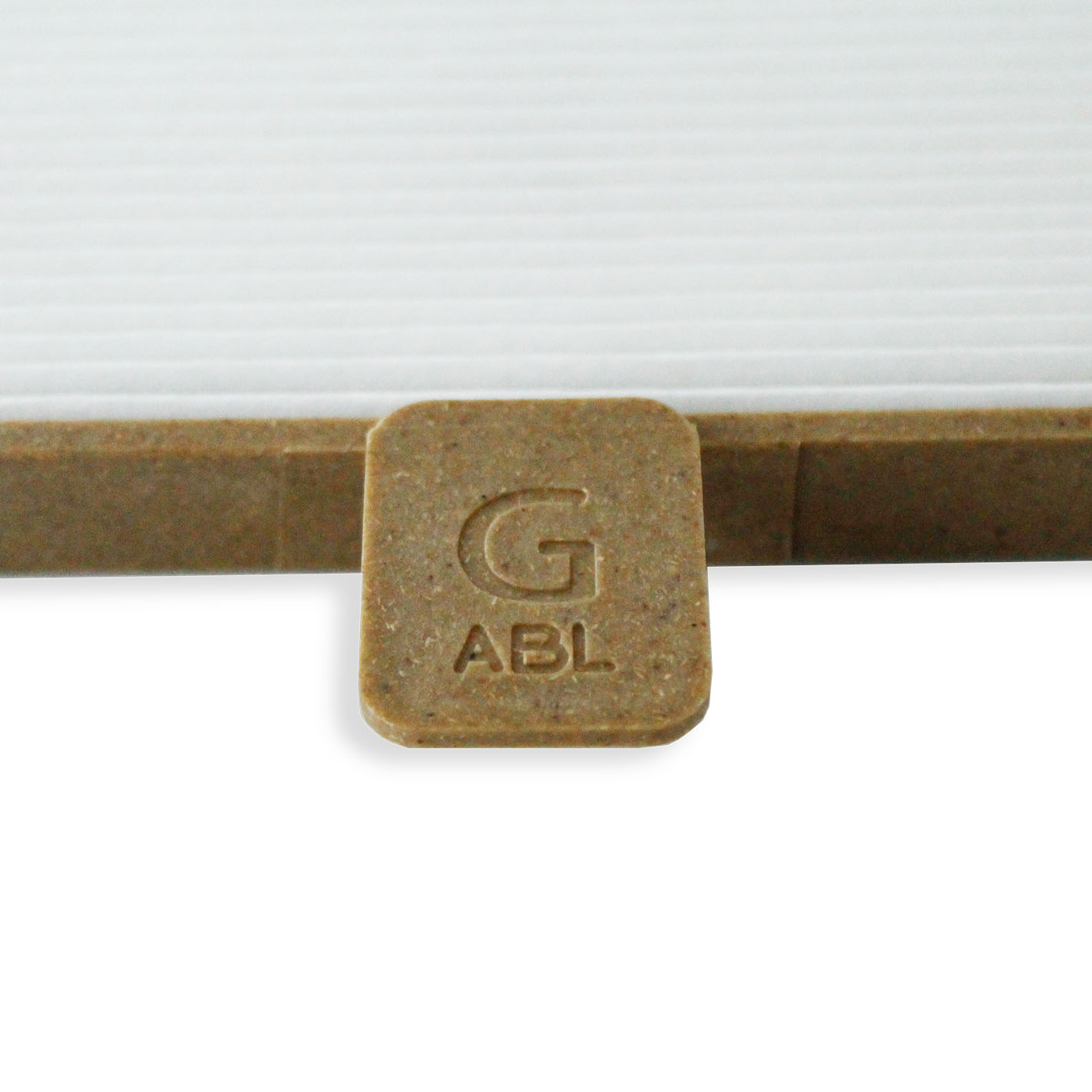 Eine braune Holzlasche mit den eingeprägten Buchstaben G und ABL liegt vor einem weißen Hintergrund.
