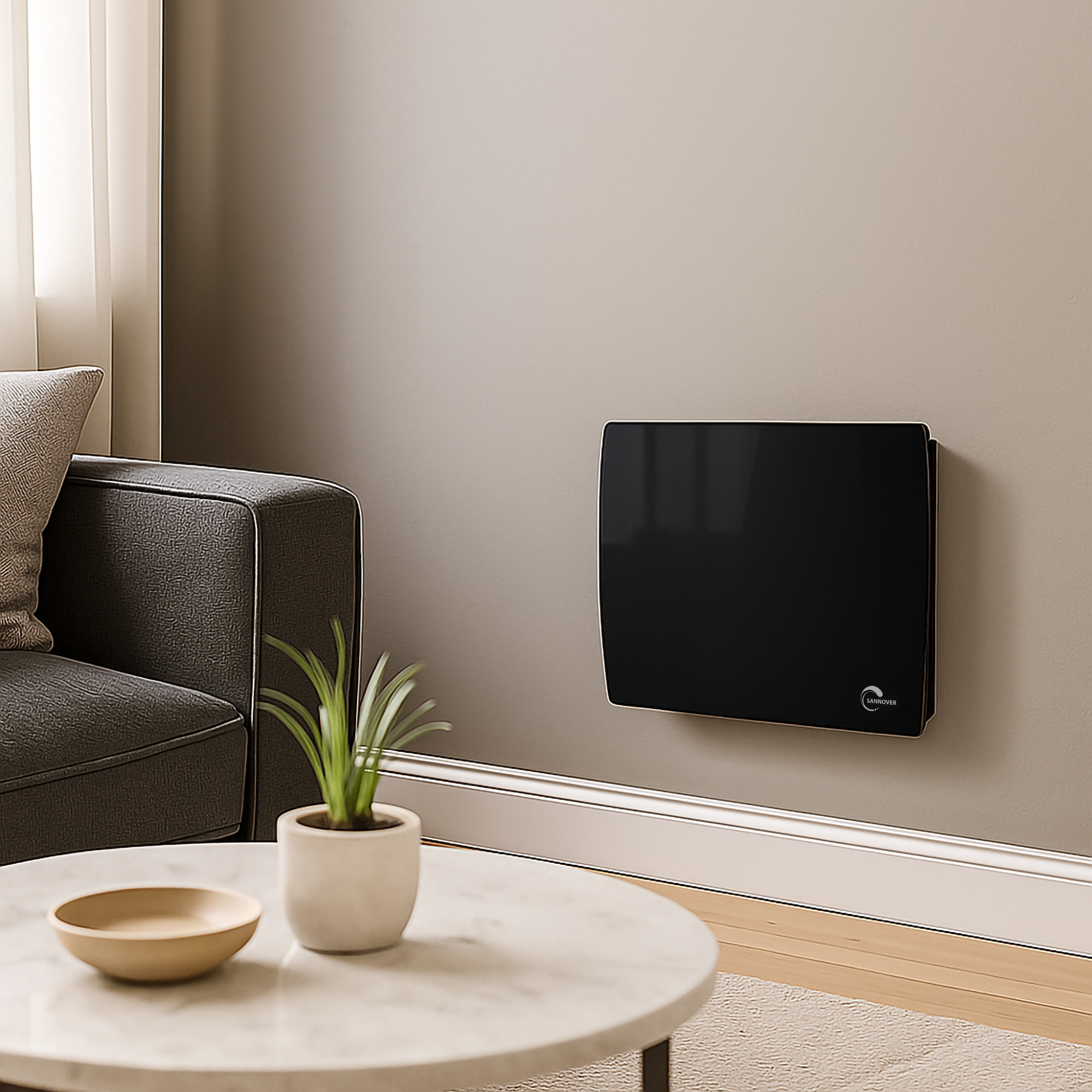 Un termosifone in vetro nero montato su una parete beige vicino a un divano grigio e a una pianta.